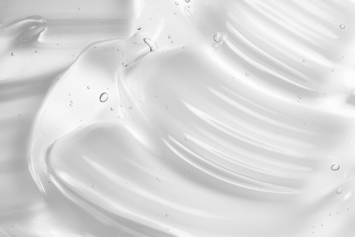 Smooth white cream texture with ripples and droplets, enriched with Alpha arbutin to restore & nourish glowing skin.