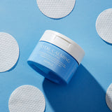 Jar of "Total Calming Toner Pads" from Avarelle placed among its white circular toner pads on a blue background.